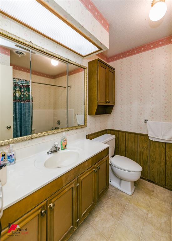 1404 North Acres Circle Springhill, LA 71075 - Photo 24 of 29 Full bathroom featuring a textured ceiling, a shower with shower curtain, vanity, wallpapered walls, and a wainscoted wall