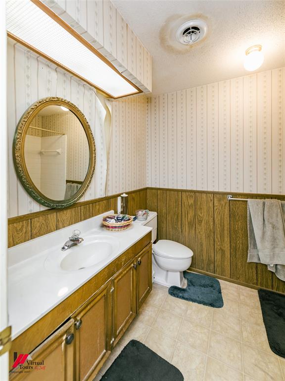 1404 North Acres Circle Springhill, LA 71075 - Photo 27 of 29 Bathroom featuring wainscoting, a textured ceiling, wooden walls, vanity, and wallpapered walls