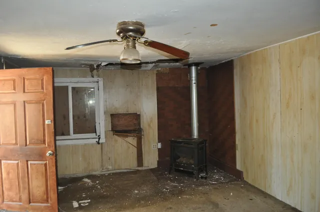 an empty room with wooden floor ceiling fan and windows