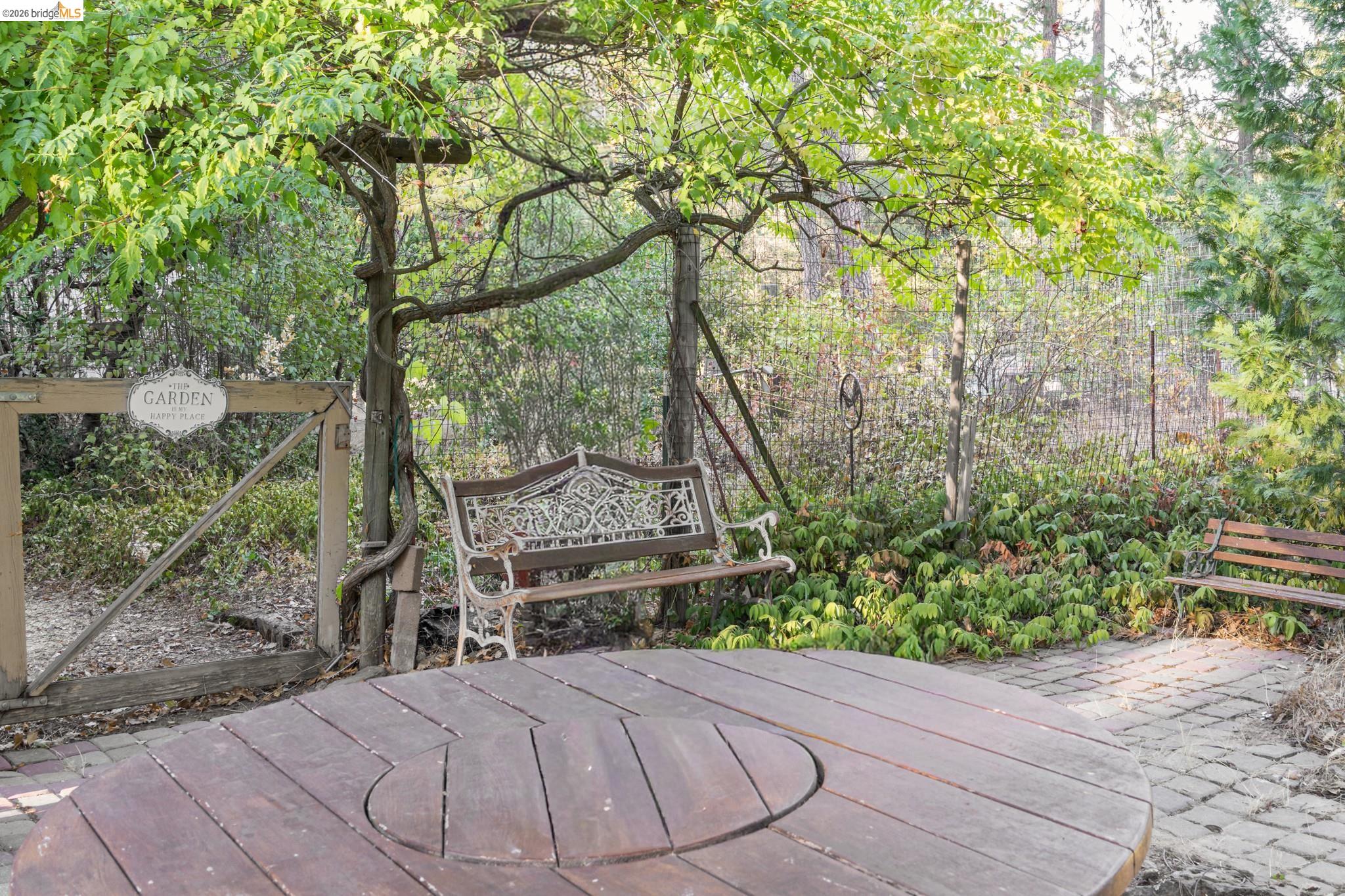 19390 Ferretti Road Groveland, CA 95321 - Photo 29 of 38 Landscaped outdoor area featuring a wood-finish circular table, brick paver patio, and mature foliage