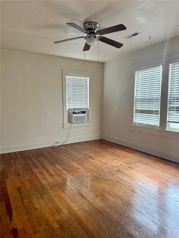 an empty room with windows and fan