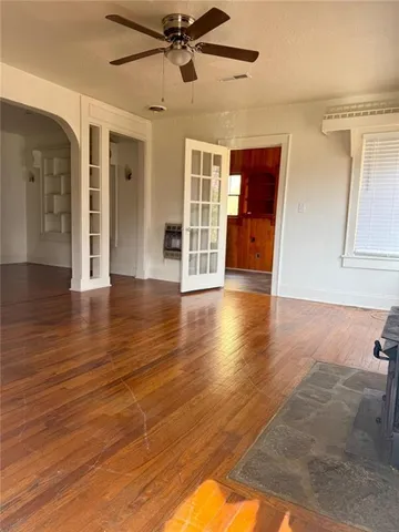 a view of an empty room with wooden floor and a ceiling fan