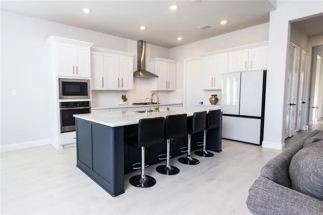 a kitchen with stainless steel appliances kitchen island granite countertop a refrigerator and a stove top oven