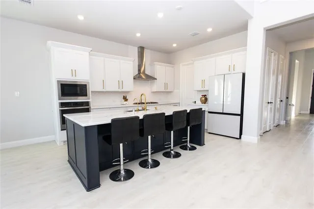 a kitchen with stainless steel appliances kitchen island granite countertop a table chairs microwave and sink