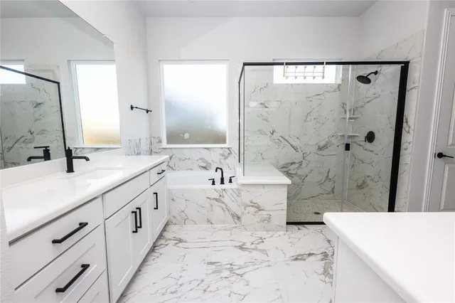 a spacious bathroom with a bathtub sink mirror and shower