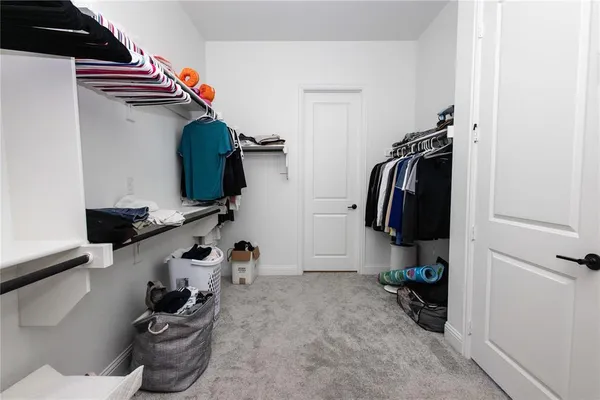 a view of walk in closet with clothes and shoes