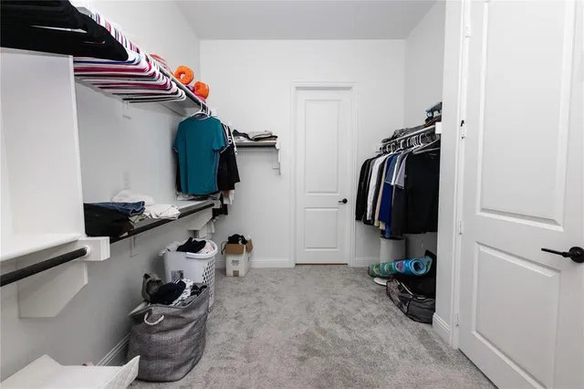 a view of walk in closet with clothes and shoes