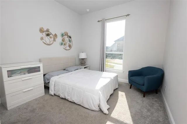 a bedroom with a bed and a chair with painting on the wall