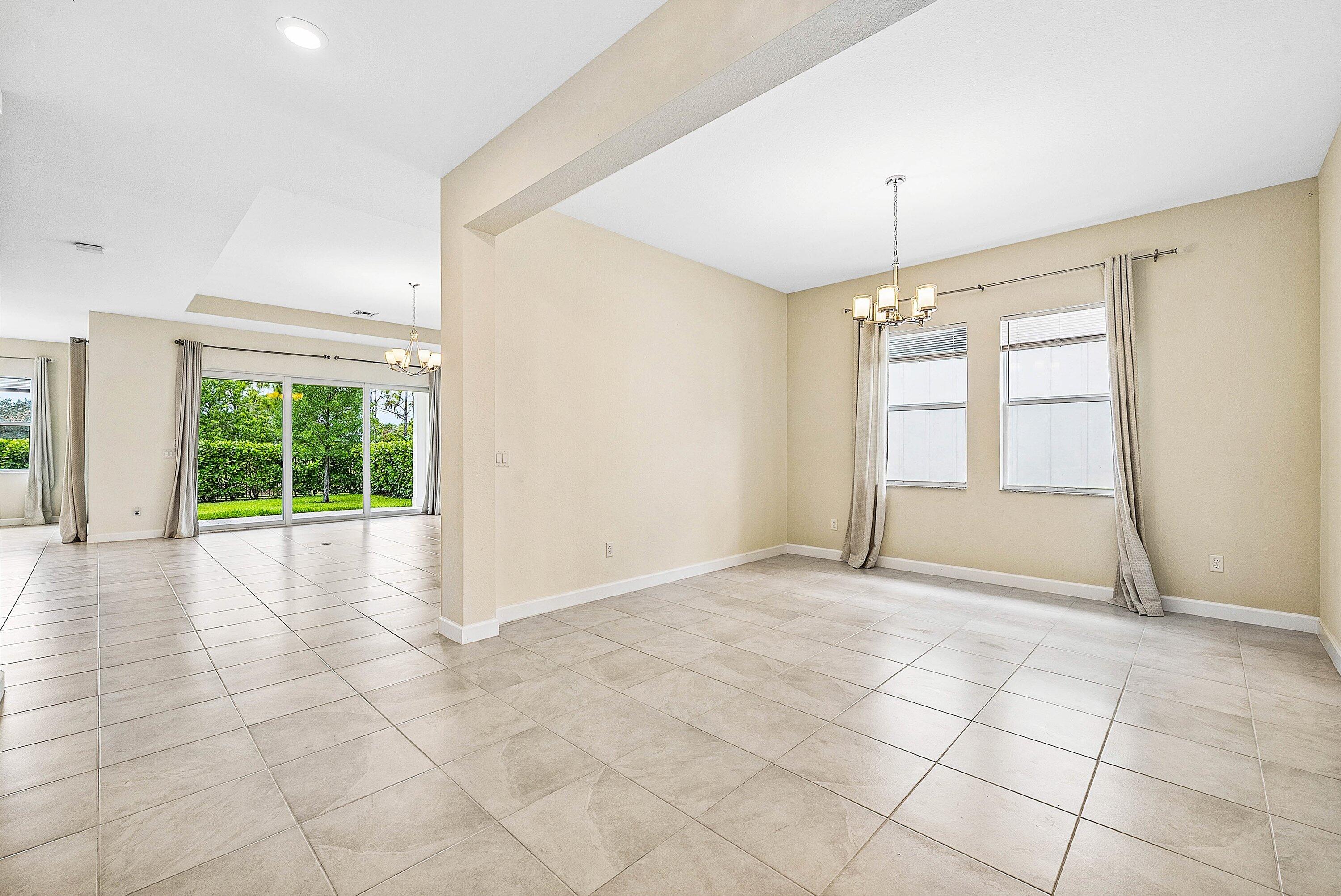 1031 Ember Ridge Run Loxahatchee, FL 33470 - Photo 19 of 52 an empty room with windows and chandelier