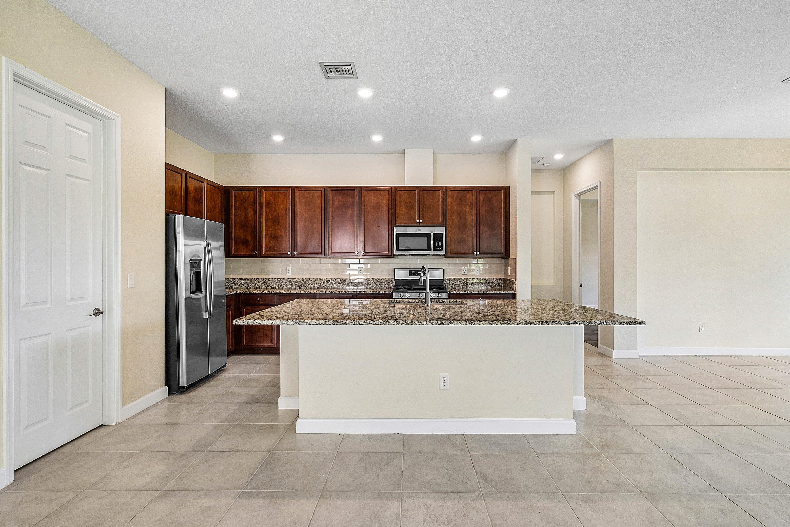 1031 Ember Ridge Run Loxahatchee, FL 33470 - Photo 23 of 52 a kitchen with stainless steel appliances granite countertop a refrigerator and a stove top oven