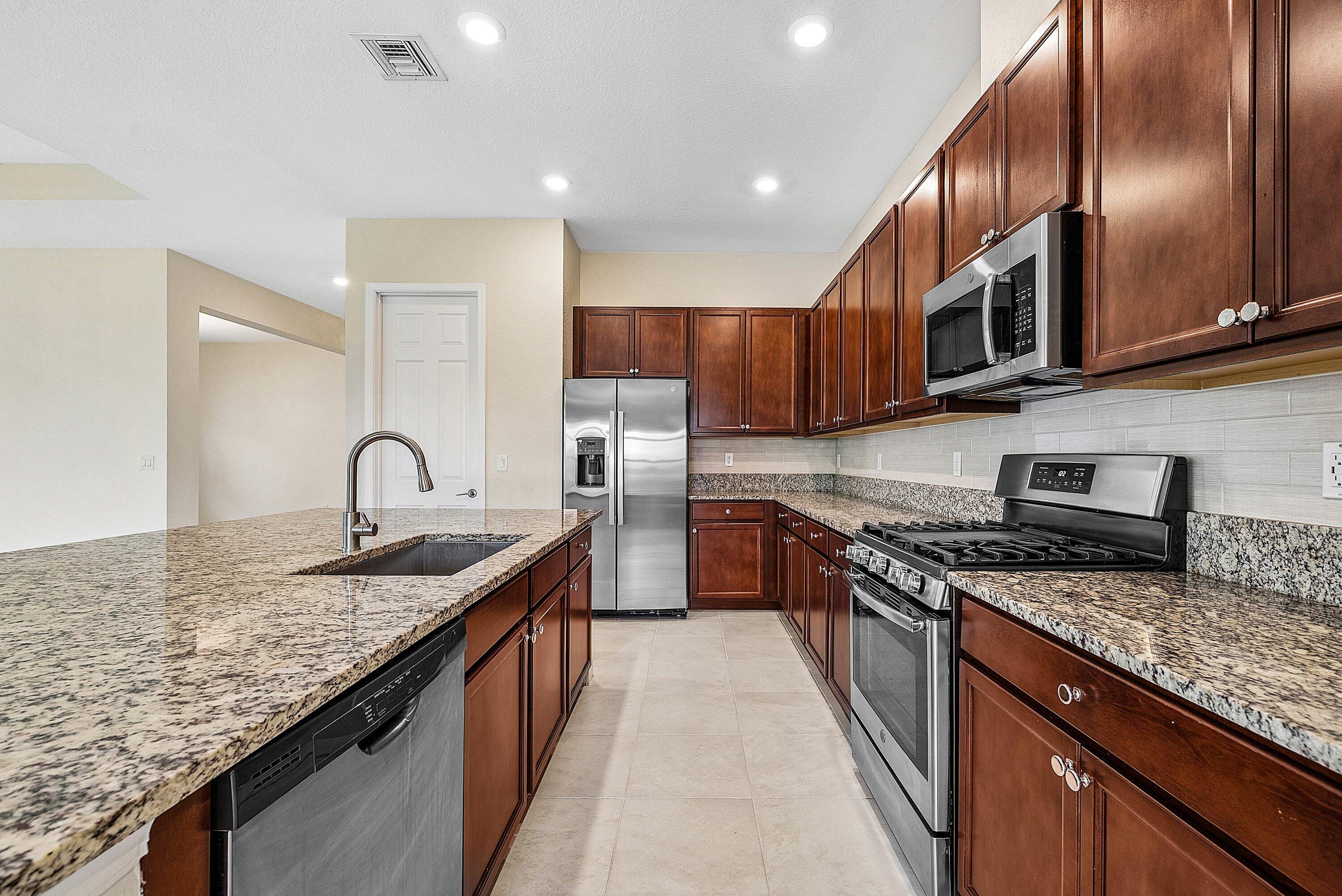 1031 Ember Ridge Run Loxahatchee, FL 33470 - Photo 24 of 52 a kitchen with stainless steel appliances granite countertop a kitchen island a stove a sink and a microwave