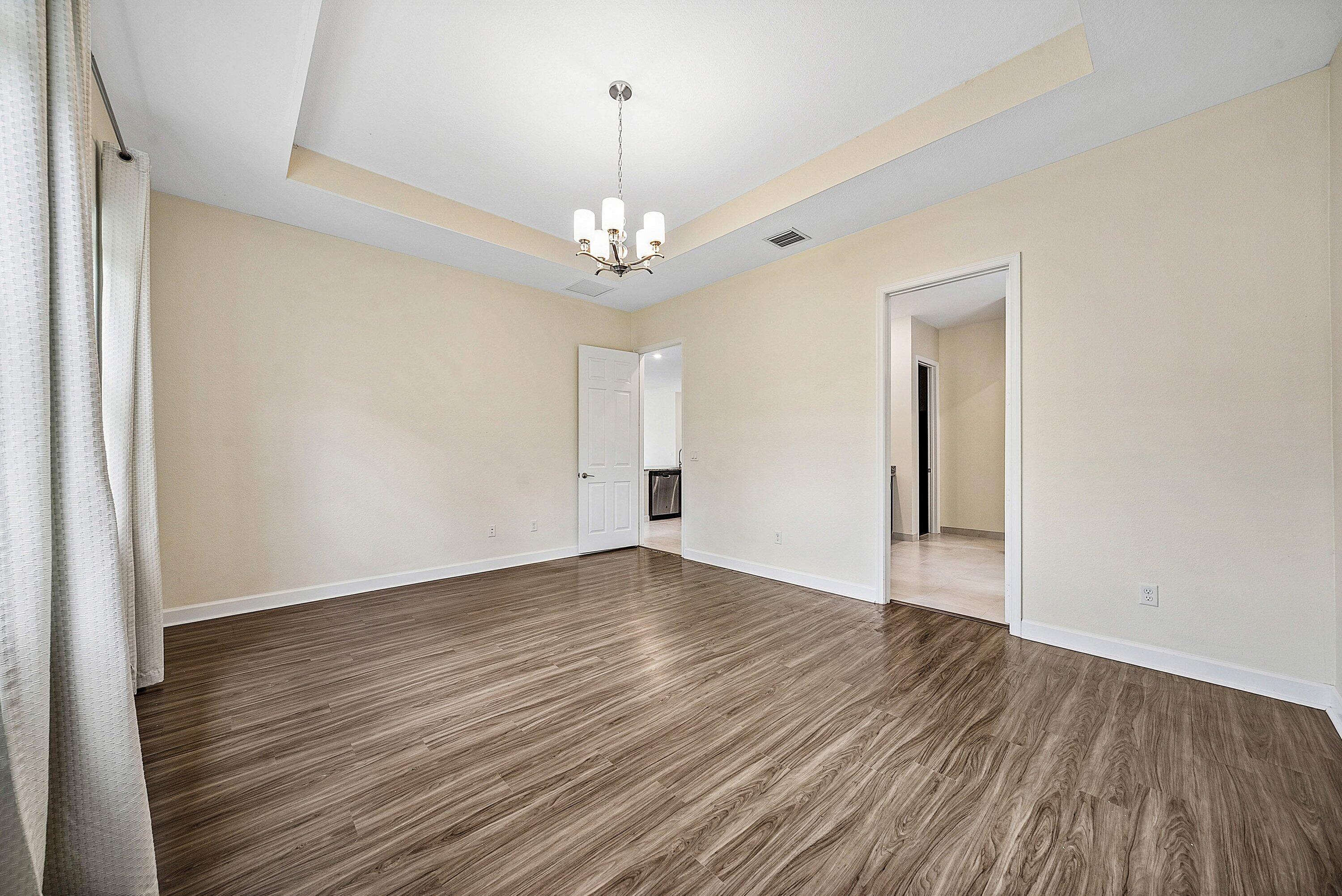 1031 Ember Ridge Run Loxahatchee, FL 33470 - Photo 29 of 52 a view of empty room with wooden floor and chandelier