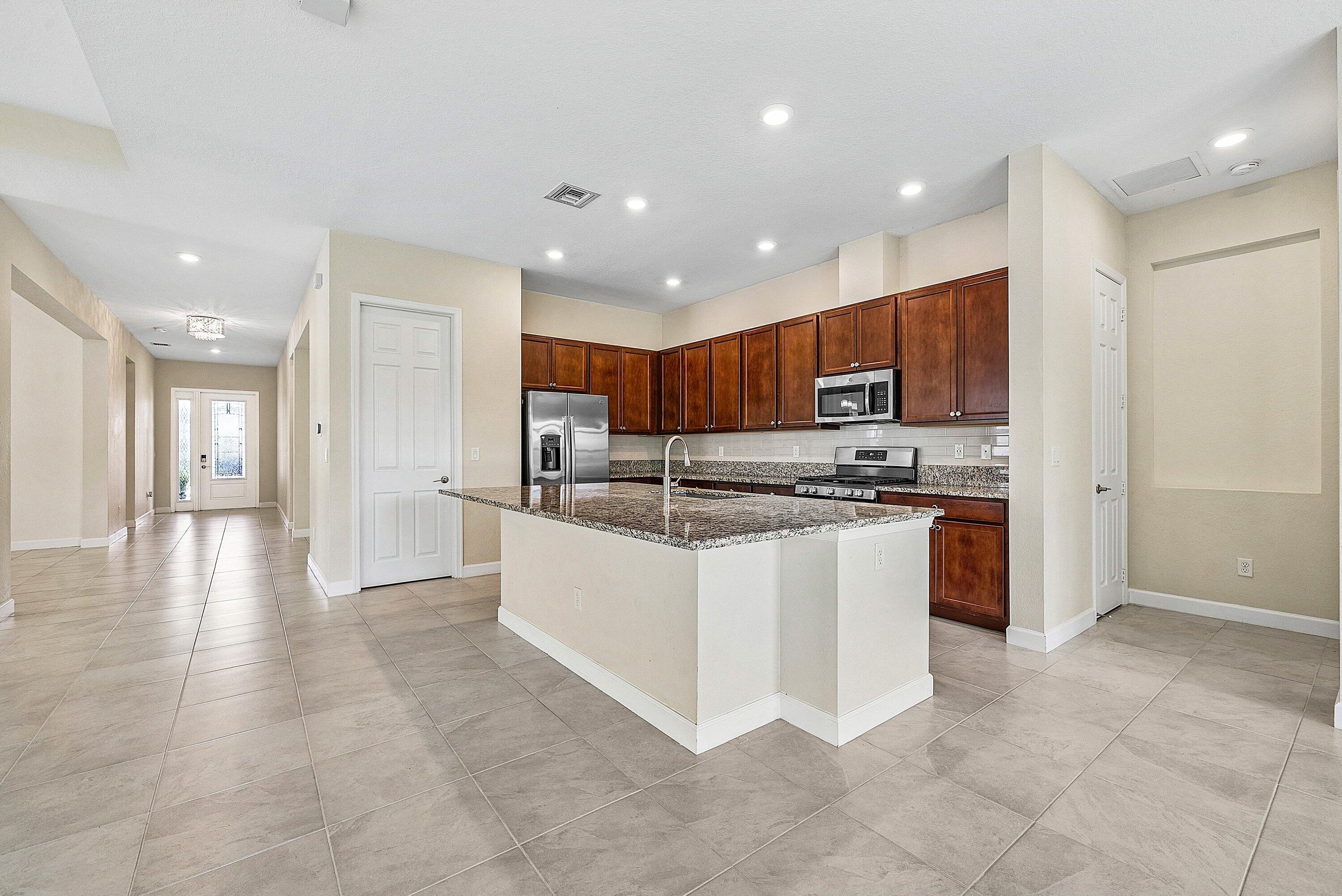 1031 Ember Ridge Run Loxahatchee, FL 33470 - Photo 9 of 52 a kitchen with stainless steel appliances granite countertop a stove top oven a sink and a refrigerator