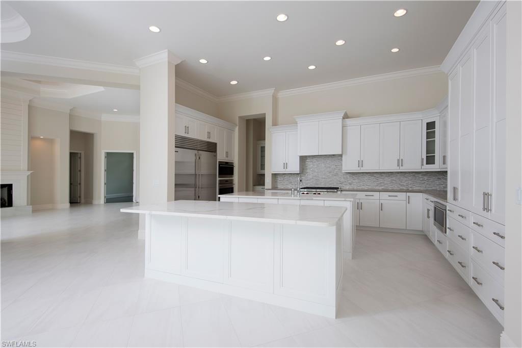 28891 Somers Drive Naples, FL 34119 - Photo 4 of 15 a large white kitchen with kitchen island a sink a center island stainless steel appliances and a cabinets
