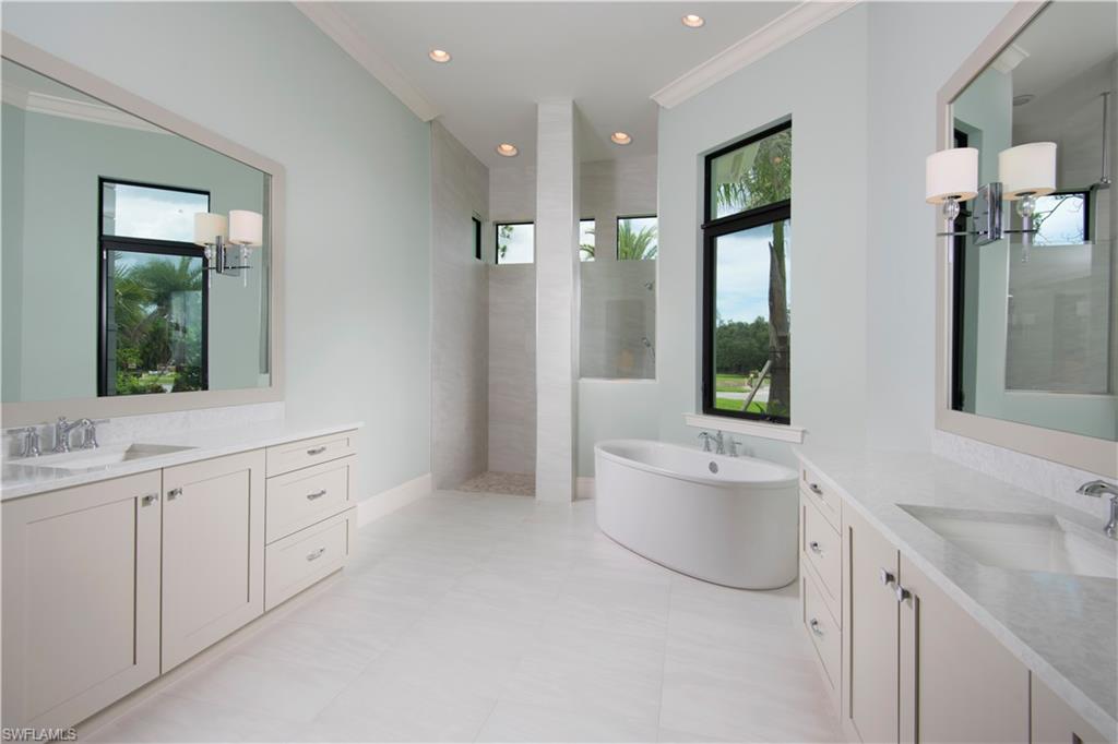 28891 Somers Drive Naples, FL 34119 - Photo 7 of 15 a spacious bathroom with a double vanity sink a large mirror and a bathtub