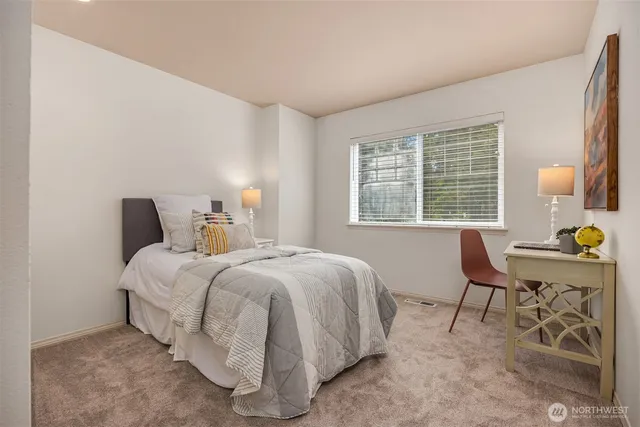 a bedroom with a bed a table and windows