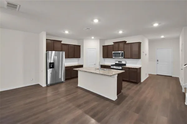 a kitchen with stainless steel appliances granite countertop a refrigerator stove top oven and cabinets