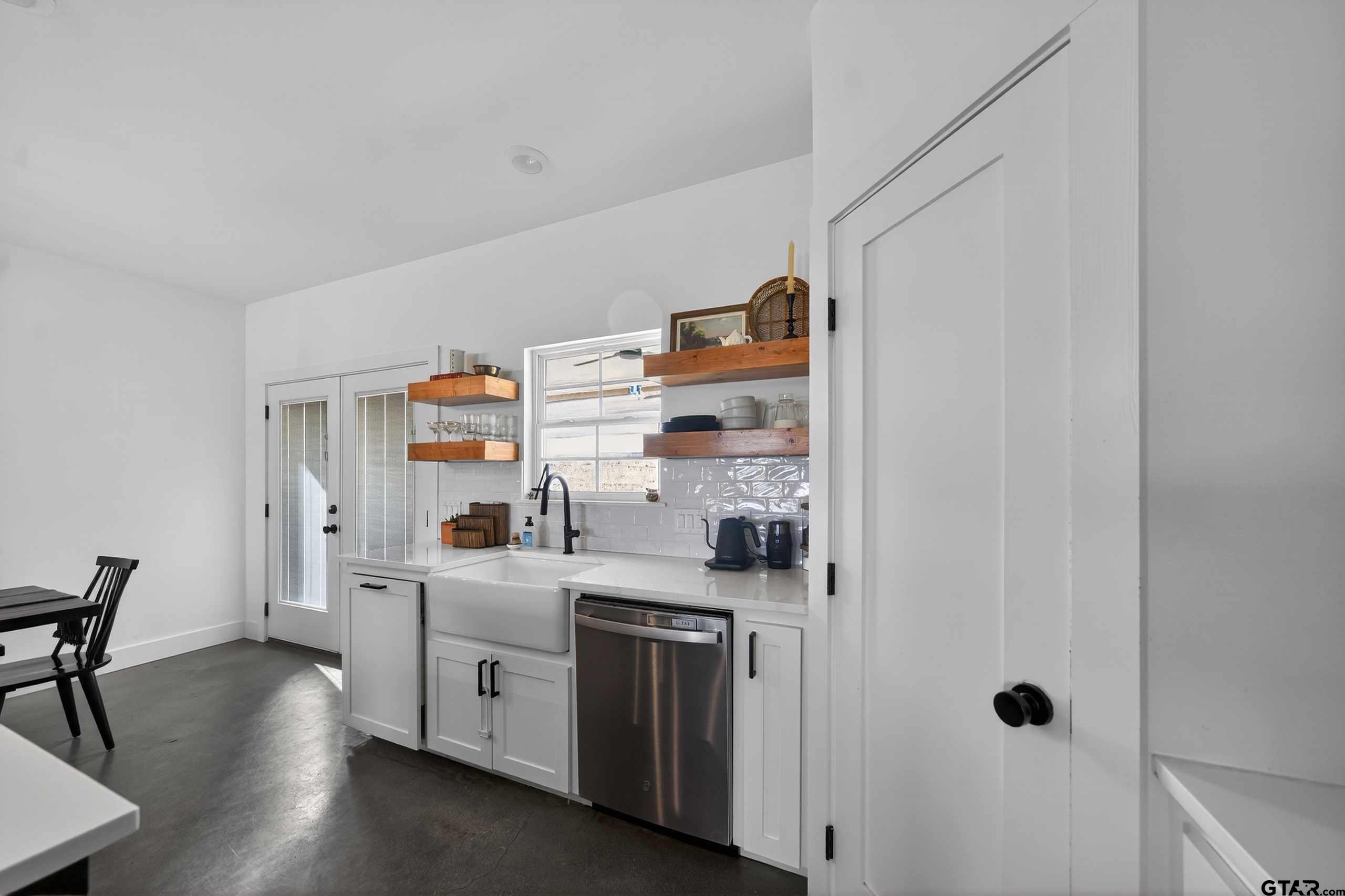 305 Gallatin Cut-Off Road Jacksonville, TX 75766 - Photo 22 of 46 a kitchen with a refrigerator a stove and a dining table with wooden floor