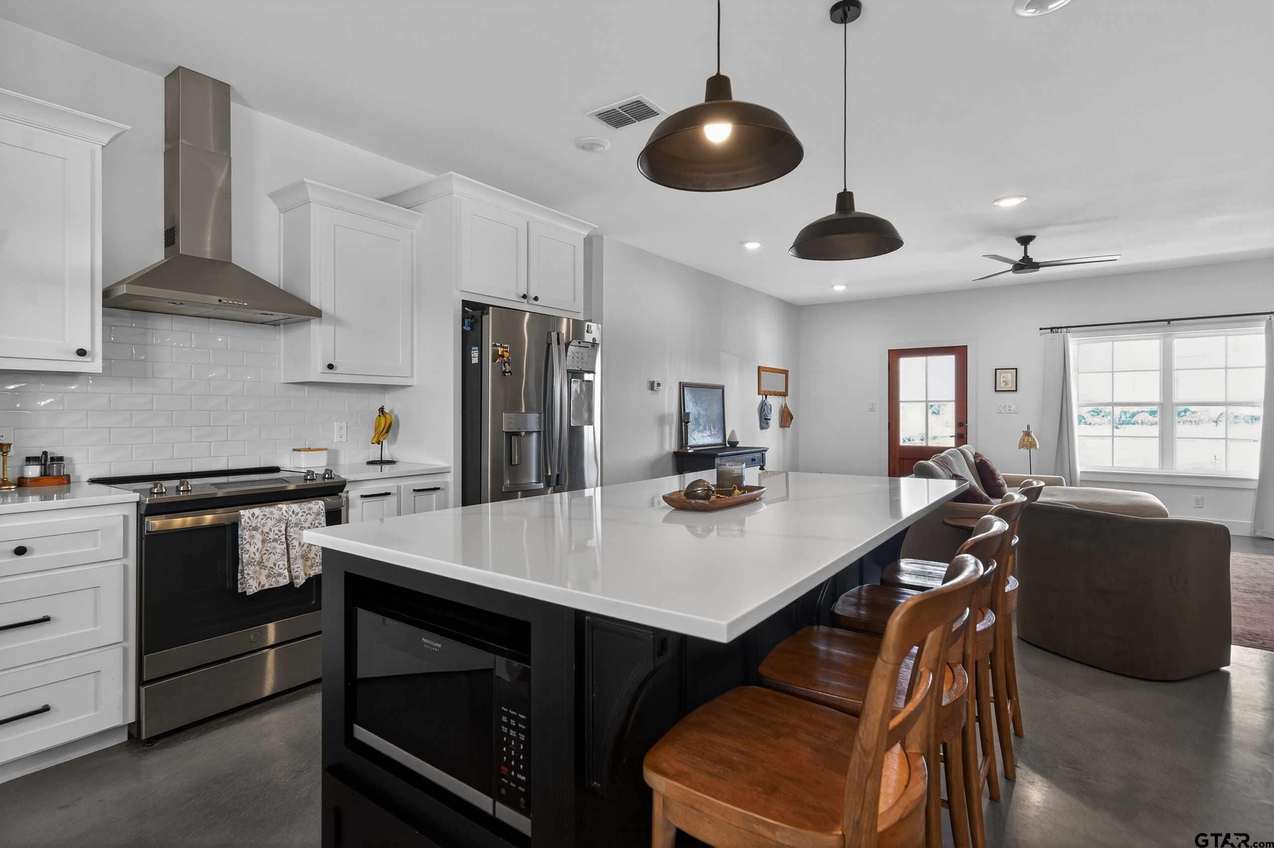 305 Gallatin Cut-Off Road Jacksonville, TX 75766 - Photo 24 of 46 a kitchen with stainless steel appliances kitchen island granite countertop a table chairs stove and refrigerator