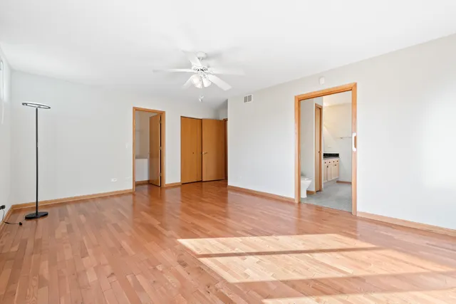 a view of empty room with wooden floor and fan