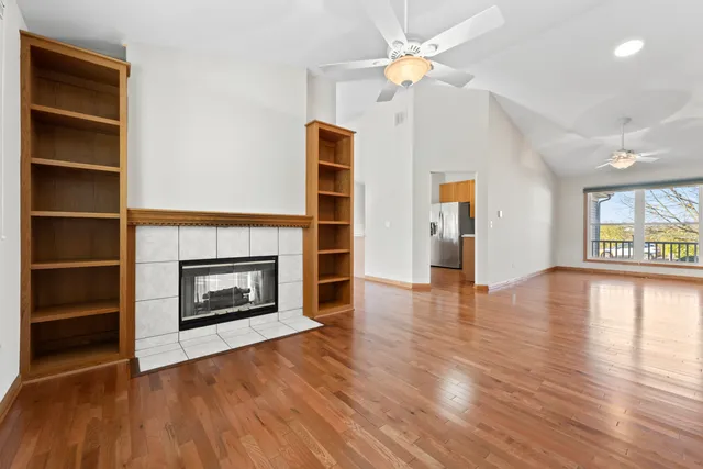 a view of an empty room with wooden floor fireplace and a window