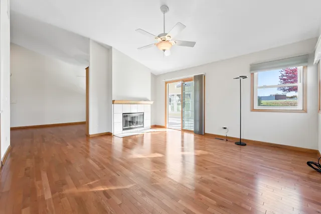 an empty room with wooden floor chandelier fan and windows