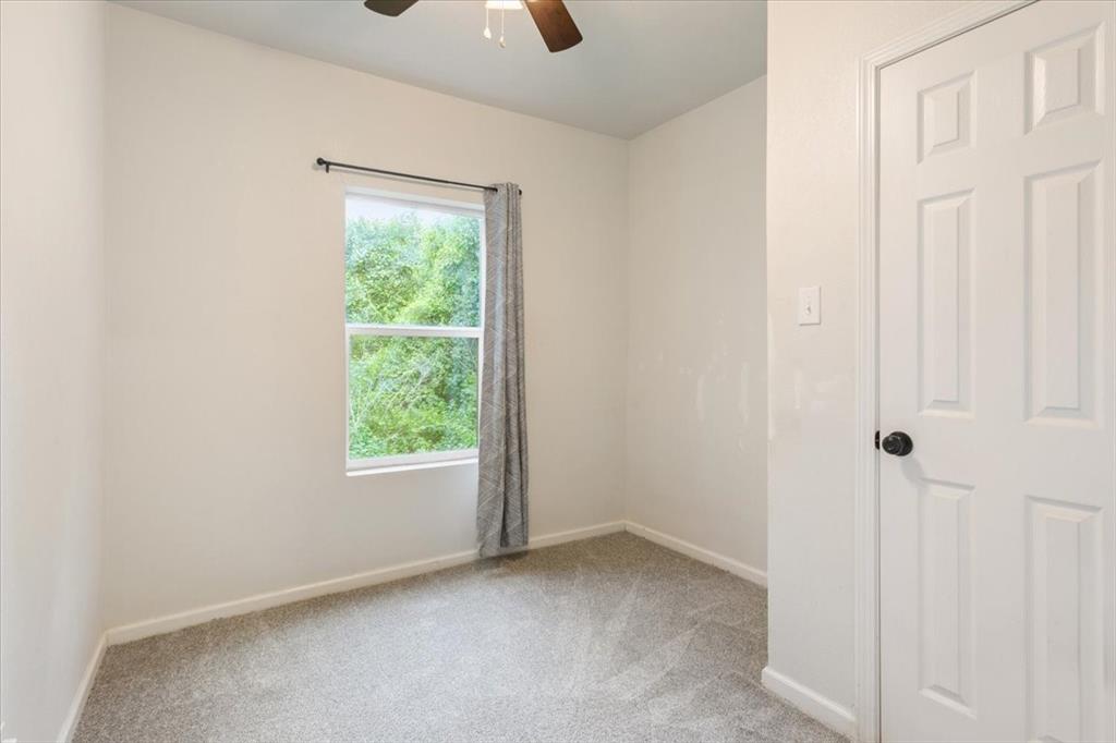 3109 North 20th Street Waco, TX 76708 - Photo 16 of 24 Bright room featuring a ceiling fan with light fixture, light gray carpeting, and a white six-panel door with black hardware