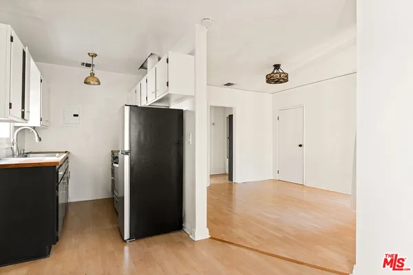 a view of a kitchen with refrigerator and white cabinets