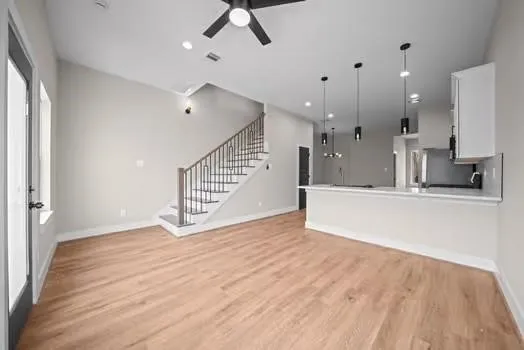 a view of an empty room with kitchen and a window