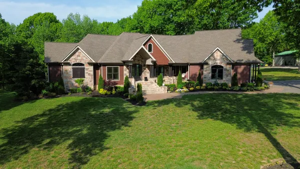 a aerial view of a house in a big yard with plants and large tree