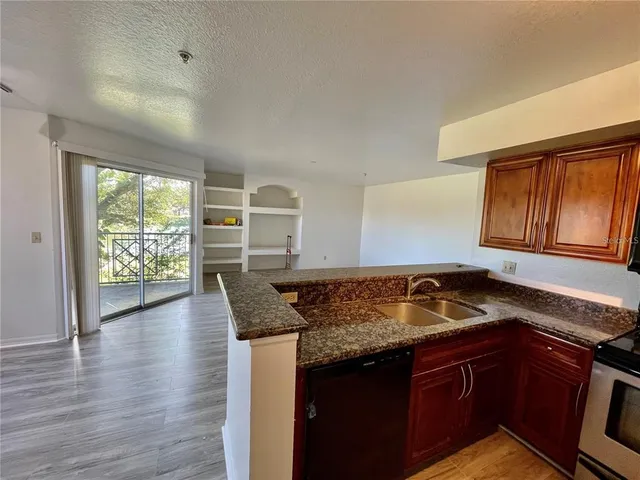 a kitchen with granite countertop a stove a sink dishwasher and cabinets with wooden floor
