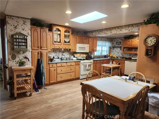 a kitchen with stainless steel appliances granite countertop a stove a refrigerator a sink a dining table and chairs with wooden floor