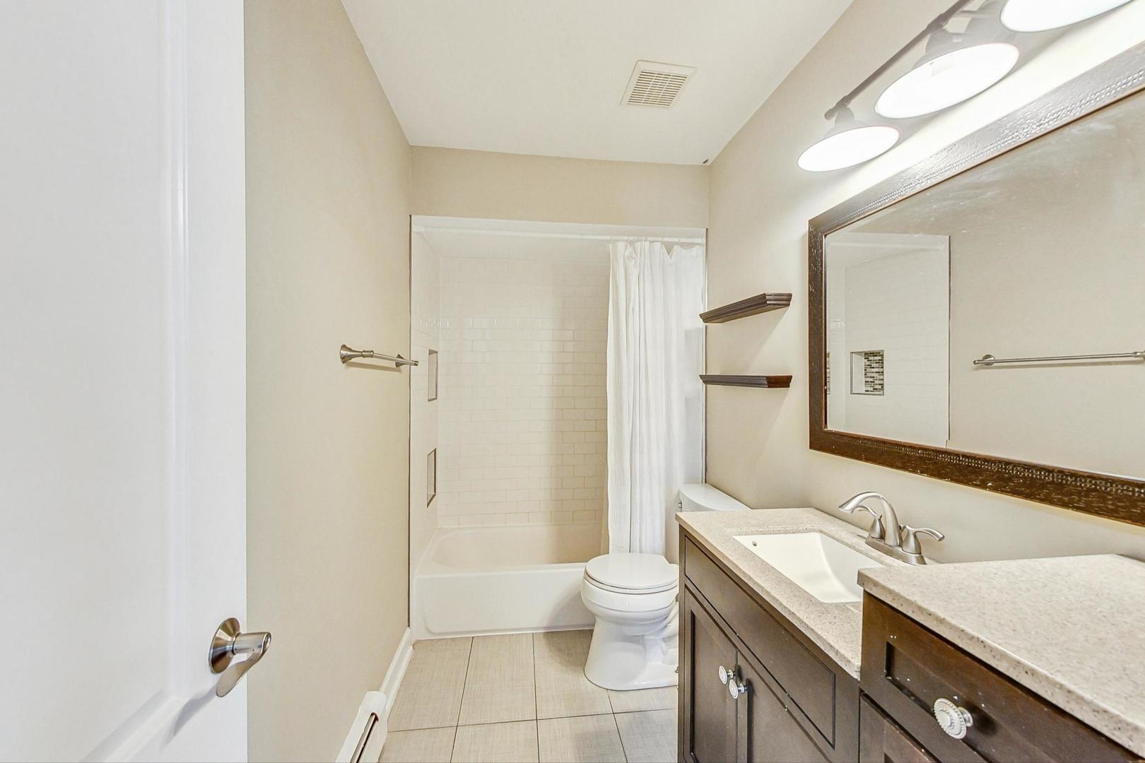19398 Wolf Road, Unit 11 Mokena, IL 60448 - Photo 22 of 27 a bathroom with a granite countertop sink a toilet and shower