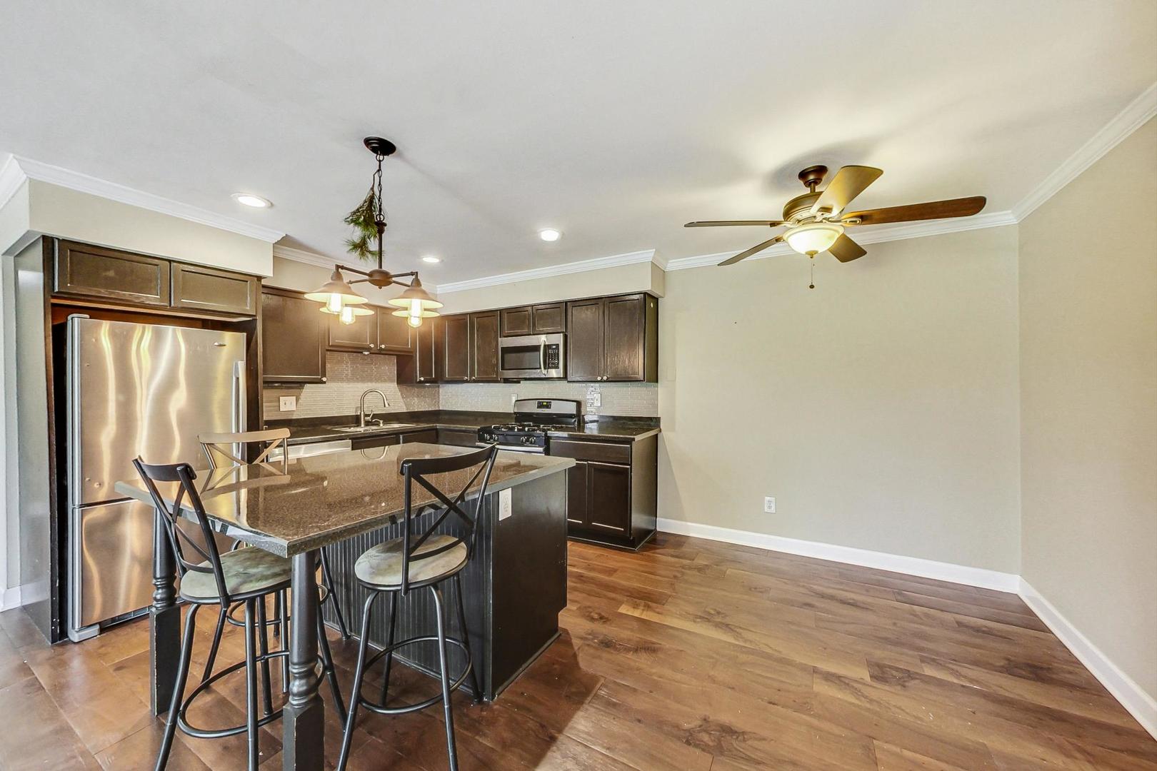 19398 Wolf Road, Unit 11 Mokena, IL 60448 - Photo 10 of 27 a kitchen with stainless steel appliances kitchen island granite countertop a table chairs and a refrigerator