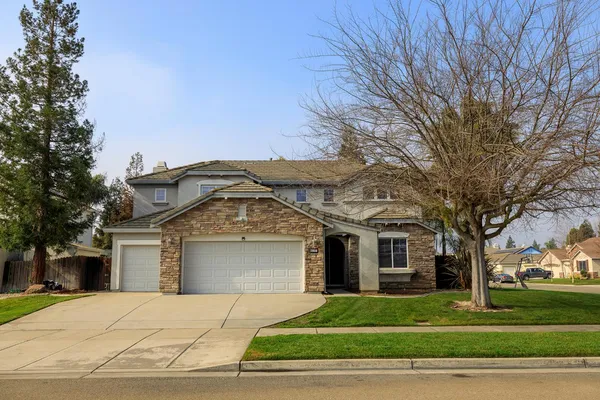 a front view of a house with a garden and trees