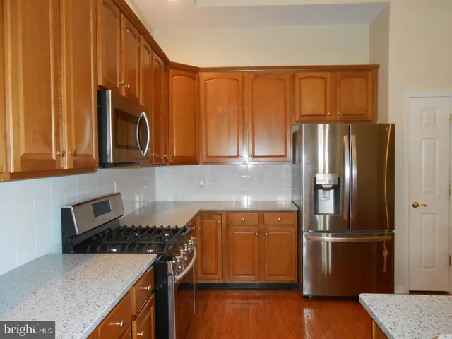 a kitchen with stainless steel appliances granite countertop a refrigerator and a stove top oven