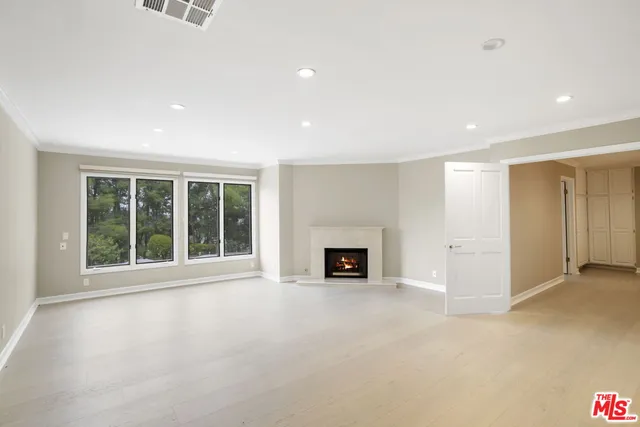 an empty room with wooden floor fireplace and windows
