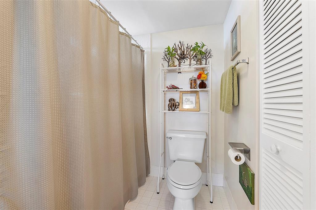 2240 North Cypress Bend Drive, Unit 908 Pompano Beach, FL 33069 - Photo 18 of 66 a bathroom with a toilet and a shower curtain