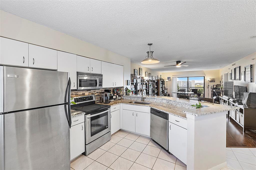 2240 North Cypress Bend Drive, Unit 908 Pompano Beach, FL 33069 - Photo 4 of 66 a kitchen with granite countertop a sink and stainless steel appliances
