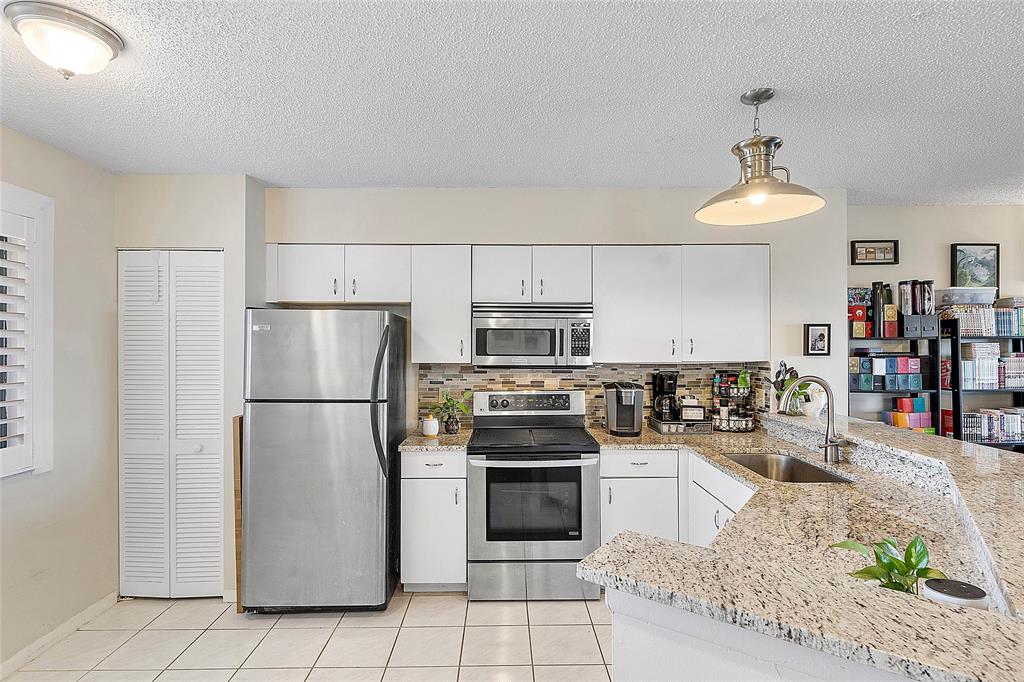 2240 North Cypress Bend Drive, Unit 908 Pompano Beach, FL 33069 - Photo 5 of 66 a kitchen with stainless steel appliances granite countertop a refrigerator sink and stove
