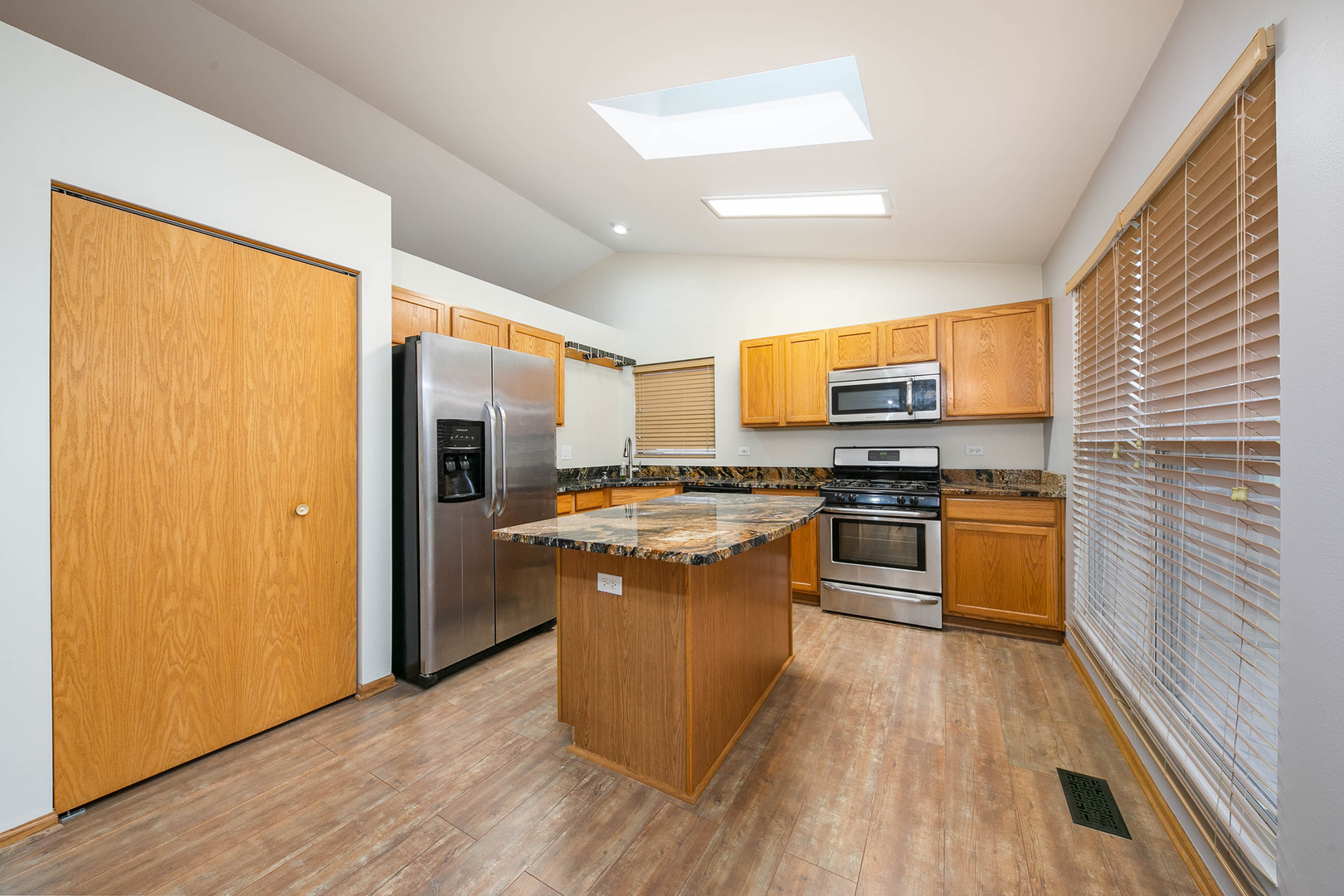 448 Bluebird Drive Bolingbrook, IL 60440 - Photo 6 of 20 a kitchen with stainless steel appliances a stove top oven a sink dishwasher a refrigerator and a dining table with wooden floor