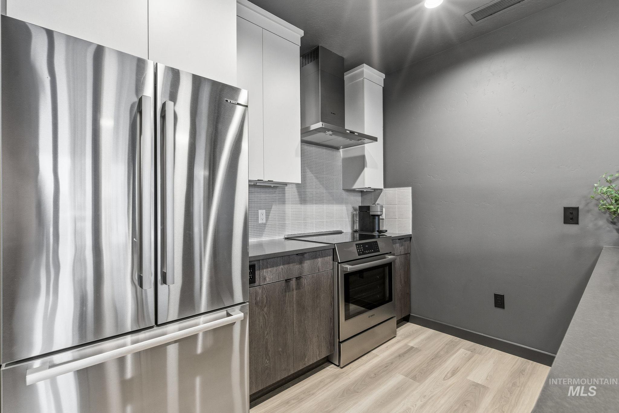 3928 East Haystack Street, Unit 107 Boise, ID 83716 - Photo 7 of 37 Kitchen with stainless steel appliances, modern cabinets, light wood finished floors, dual tone cabinets, and backsplash