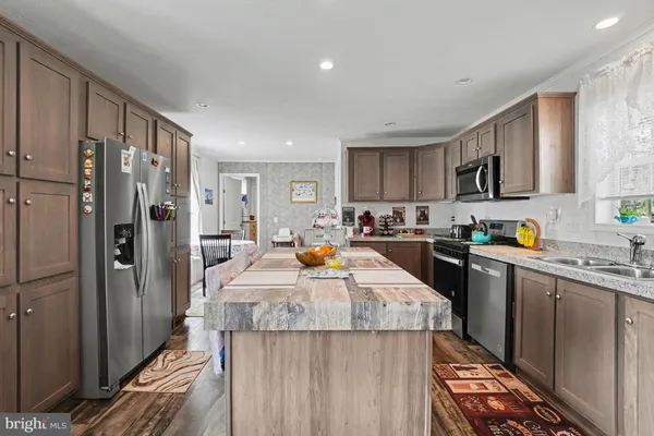 a kitchen with stainless steel appliances kitchen island granite countertop a refrigerator and a stove top oven