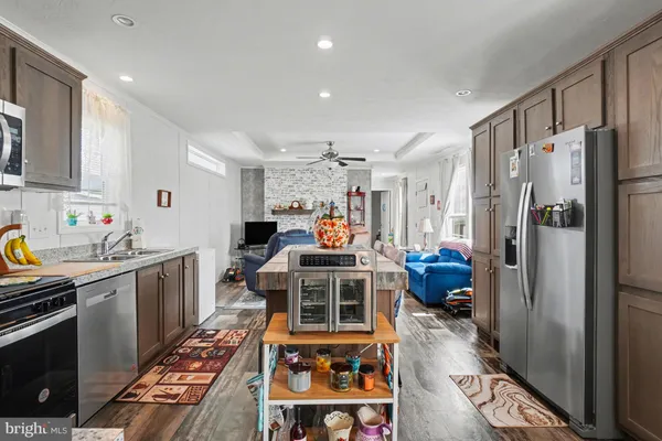 a very nice looking kitchen with stainless steel appliances granite countertop a stove a refrigerator and a dining table with wooden floor