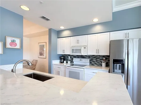 a kitchen with stainless steel appliances kitchen island granite countertop a refrigerator and a stove top oven
