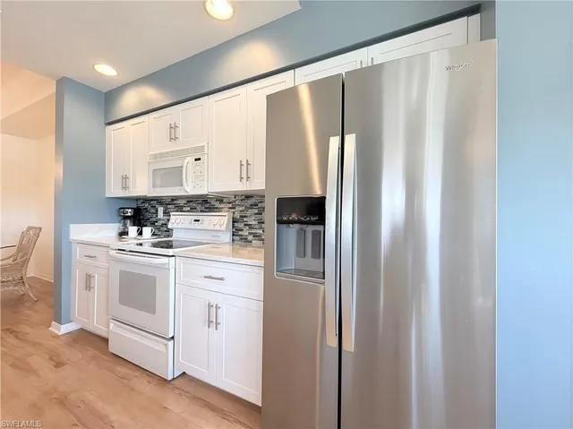 a kitchen with stainless steel appliances white cabinets and a refrigerator