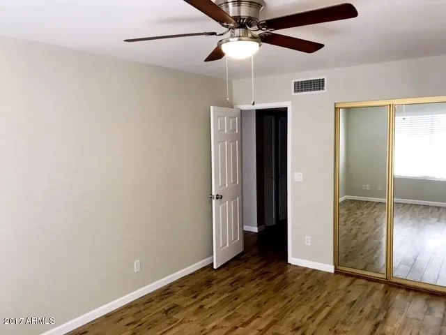 an empty room with wooden floor closet and ceiling fan