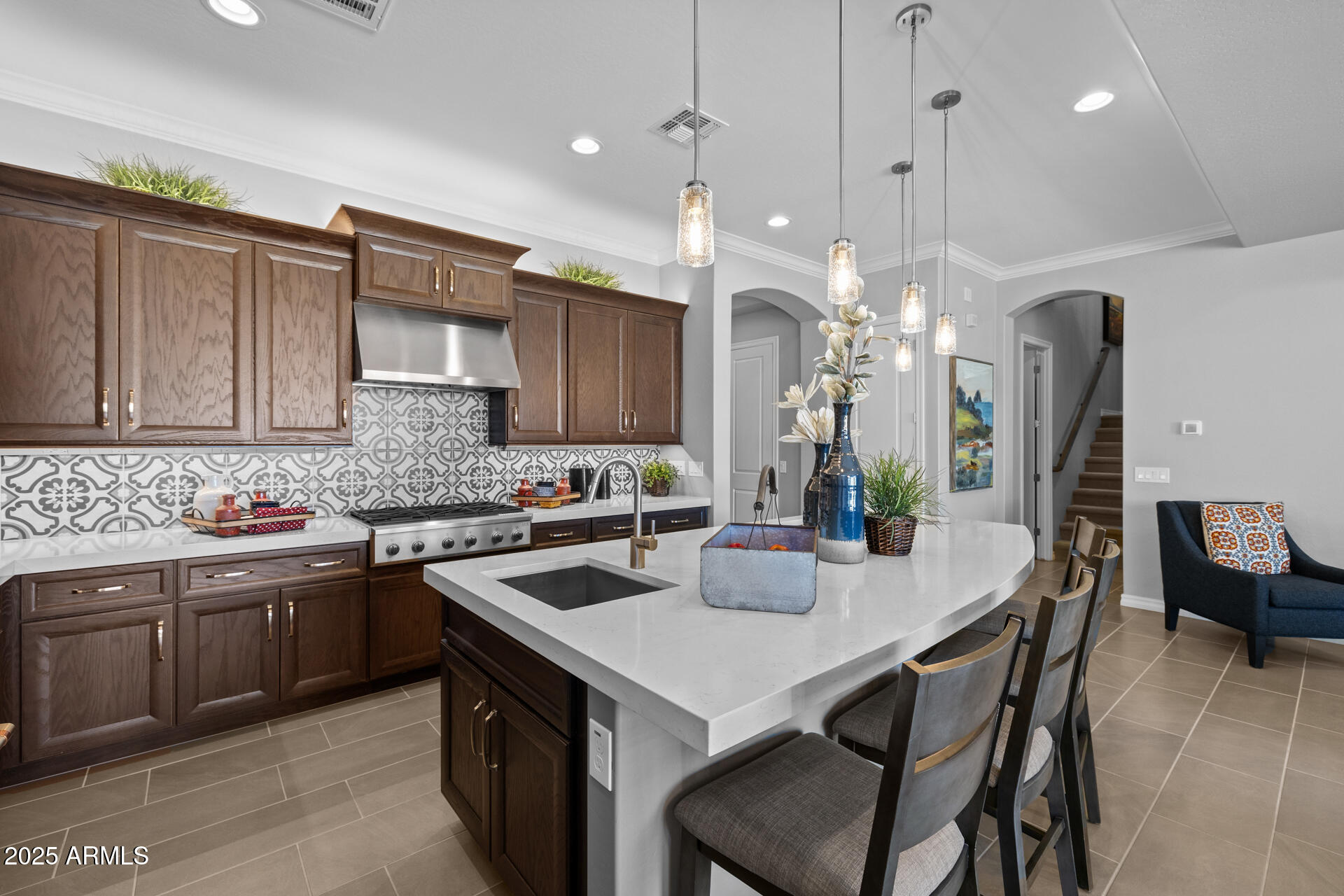 4273 East John Street Gilbert, AZ 85295 - Photo 9 of 29 a kitchen with a stove a sink a kitchen island with chairs and wooden cabinets