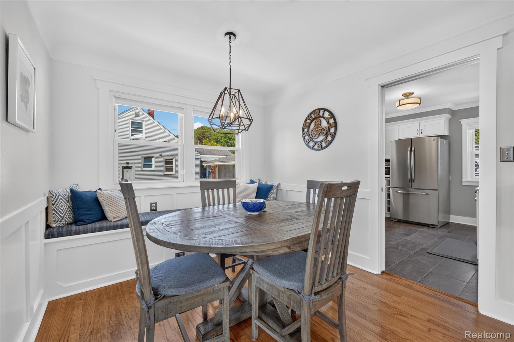 4112 Durham Road Royal Oak, MI 48073 - Photo 11 of 38 Hardwood flooring, geometric pendant light fixture, built-in window seating, wainscoting, and an open doorway to the kitchen with tile flooring