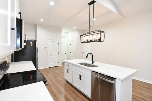 a kitchen with stainless steel appliances a white stove top oven a sink dishwasher and a refrigerator with wooden floor